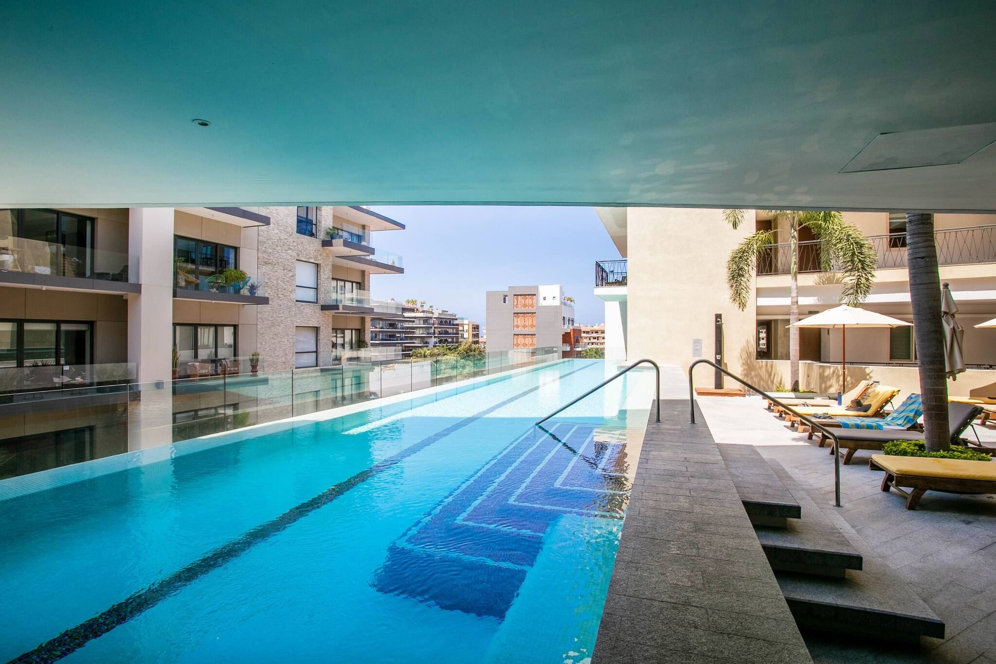 A swimming pool with a clear view of the surrounding buildings and a lounge area with sun loungers.