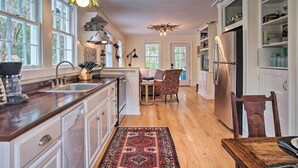 A spacious kitchen with wooden countertops, a central island, and a dining area with a patterned rug. - Savannah Cottage - 5 Mi to Wormsloe Historic Site! (Savannah)
