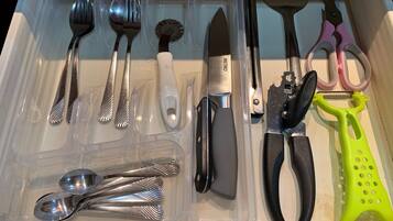 A drawer containing various kitchen utensils including spoons, a knife, and a grater.