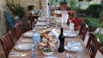 A dining table set for a meal with chairs, plates, cutlery, and a bottle of wine.