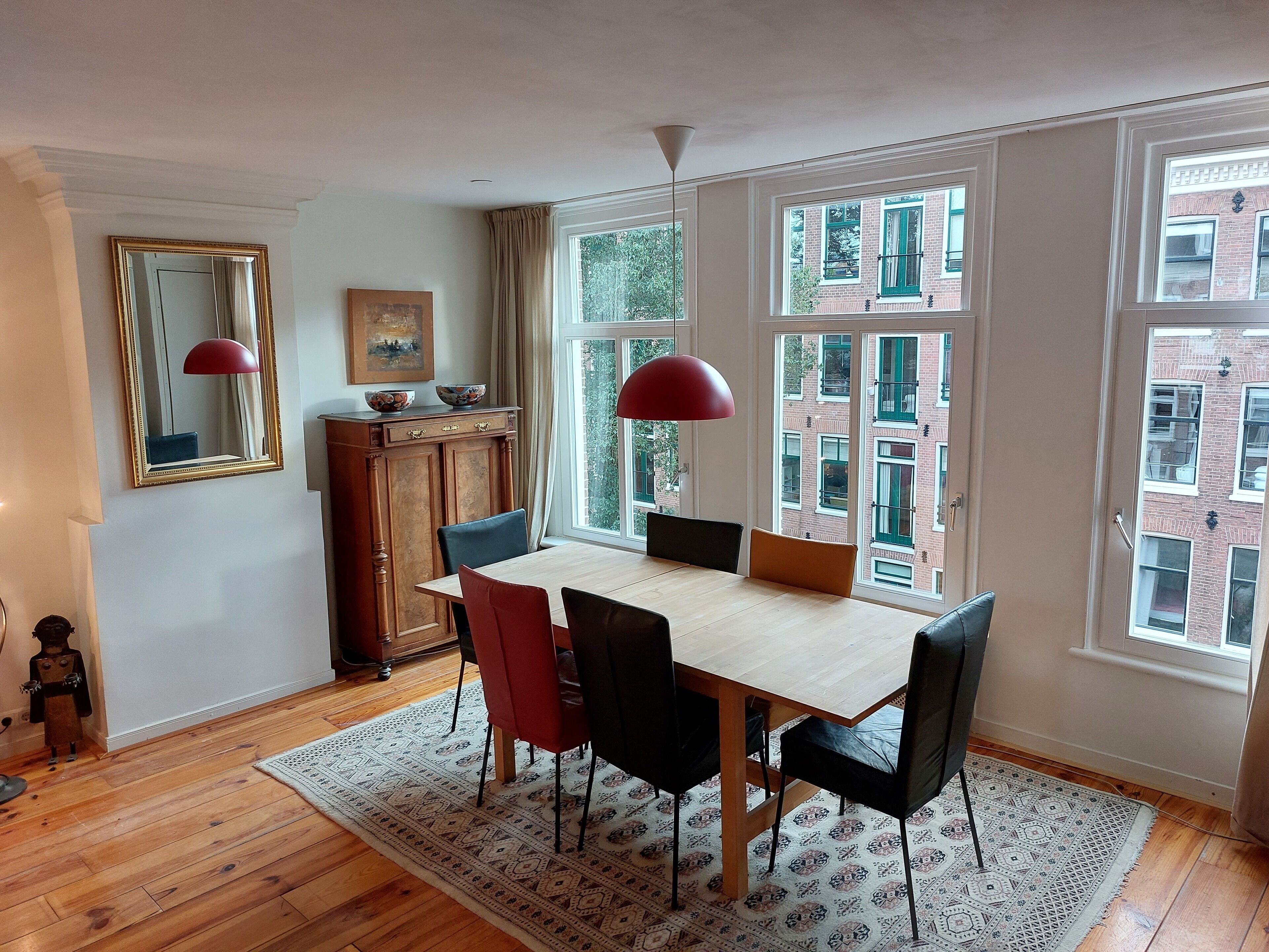 A dining area with a wooden table, chairs, and a patterned rug.