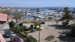 A marina with numerous boats docked, a parking area with cars, and a clear view of the sea. - Holiday Home Alle Pavoncelle, independent with terrace of 50 sqm (Portoscuso)