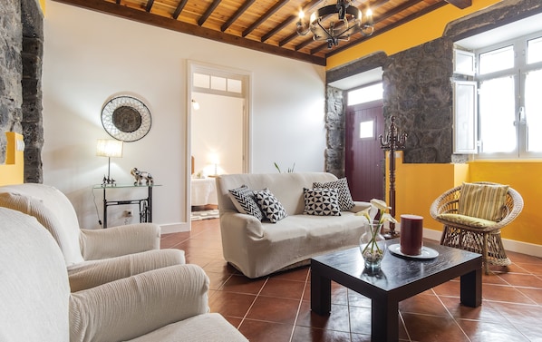 A cozy living room with a sofa, armchairs, a coffee table, and a stone wall. - Farmhouse (Mountain View) (Lomba da Fazenda)