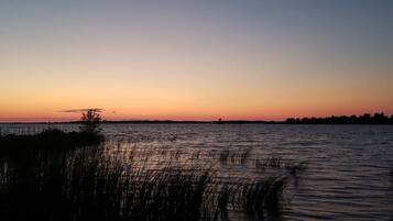 A calm body of water at sunset with a distant shoreline silhouette.