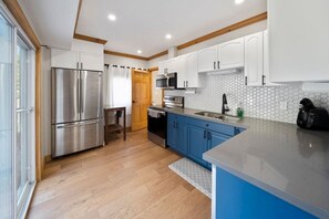 Una cocina moderna con electrodomésticos de acero inoxidable, armarios azules y un amplio ventanal.