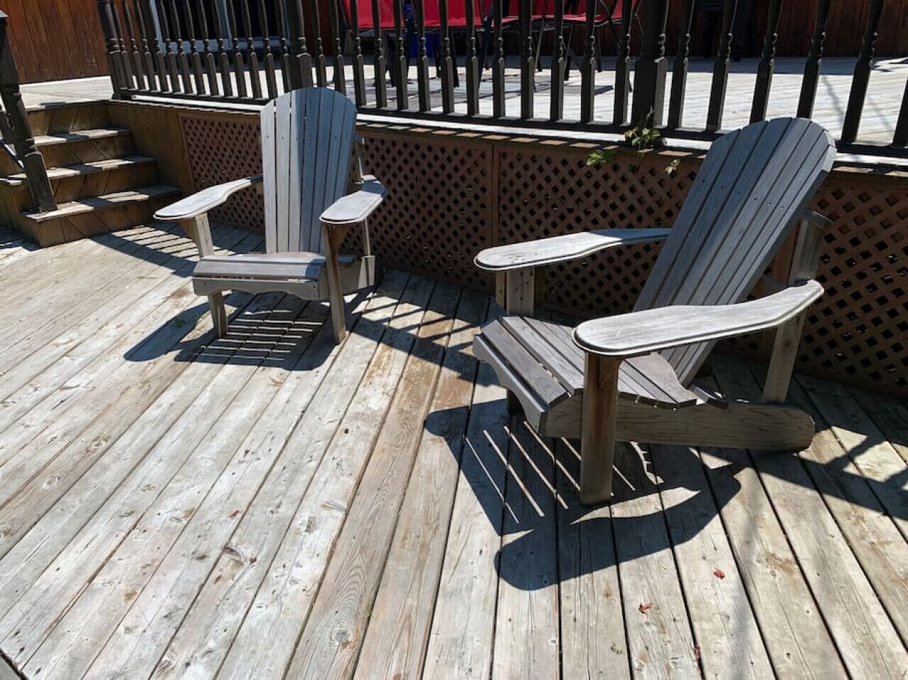 A wooden deck with Adirondack chairs and a small table.