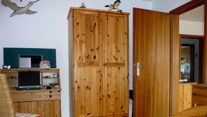 Una habitación con un armario de madera, un escritorio con una computadora portátil, una silla y una cama.