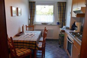 Una cocina compacta con una mesa y sillas, una ventana con cortinas y una estufa.