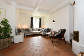 Un salón con sofá, sillones, una mesita, lámpara de pie, chimenea y una planta en maceta.