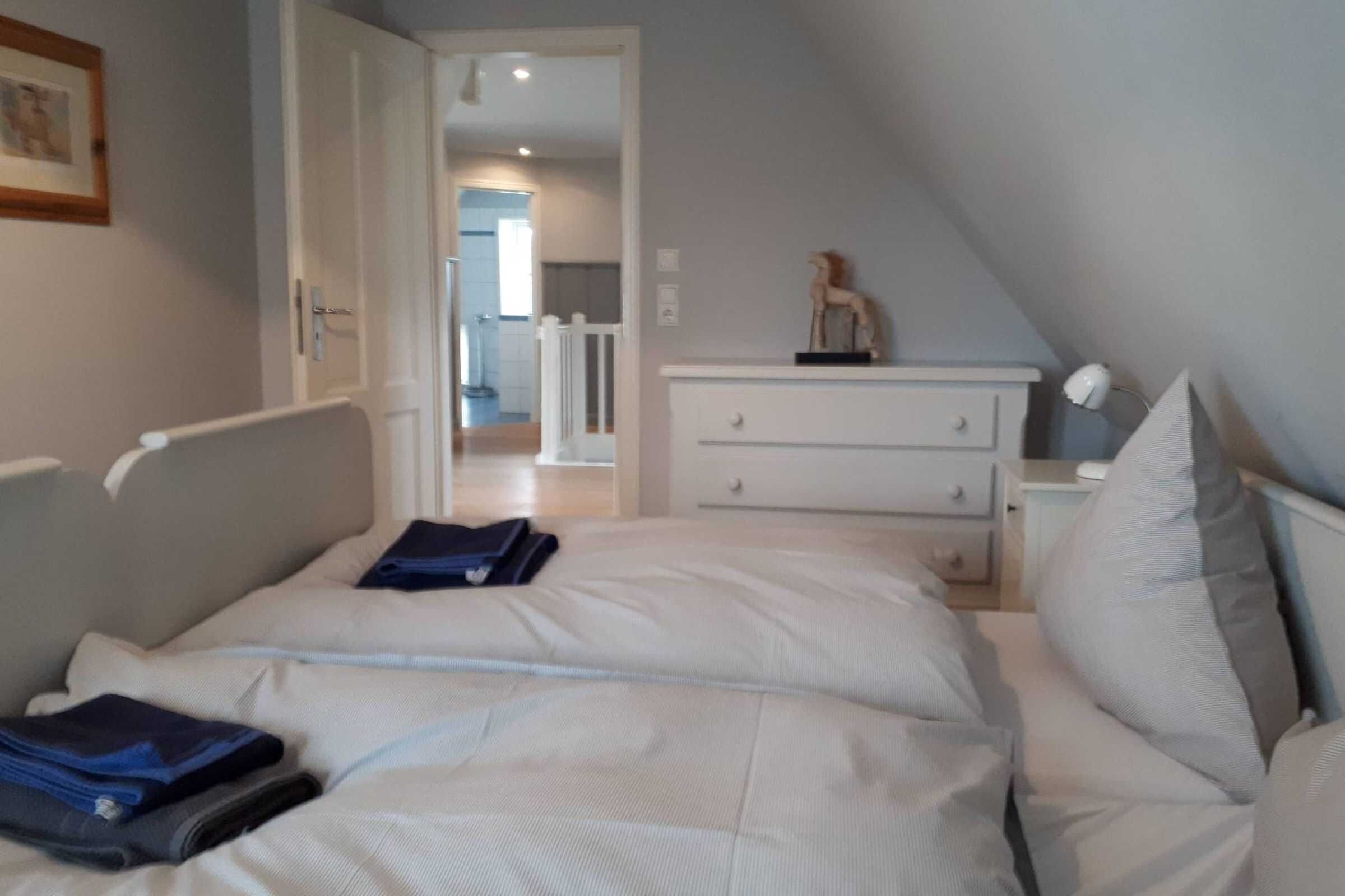 Et soveværelse med seng, natbord, kommode og en dør til et andet rum.