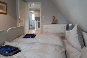 Et soveværelse med seng, natbord, kommode og en dør til et andet rum.