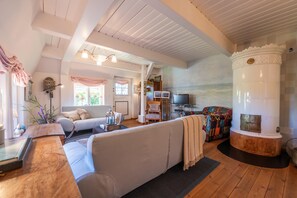 A cozy living room with a sofa, a fireplace, and a television. - Anno, Whg Anne Bonney Nr. 2, part of the house - Anno, Whg Anne Bonney Nr. 2, part of the house * (Süderende)