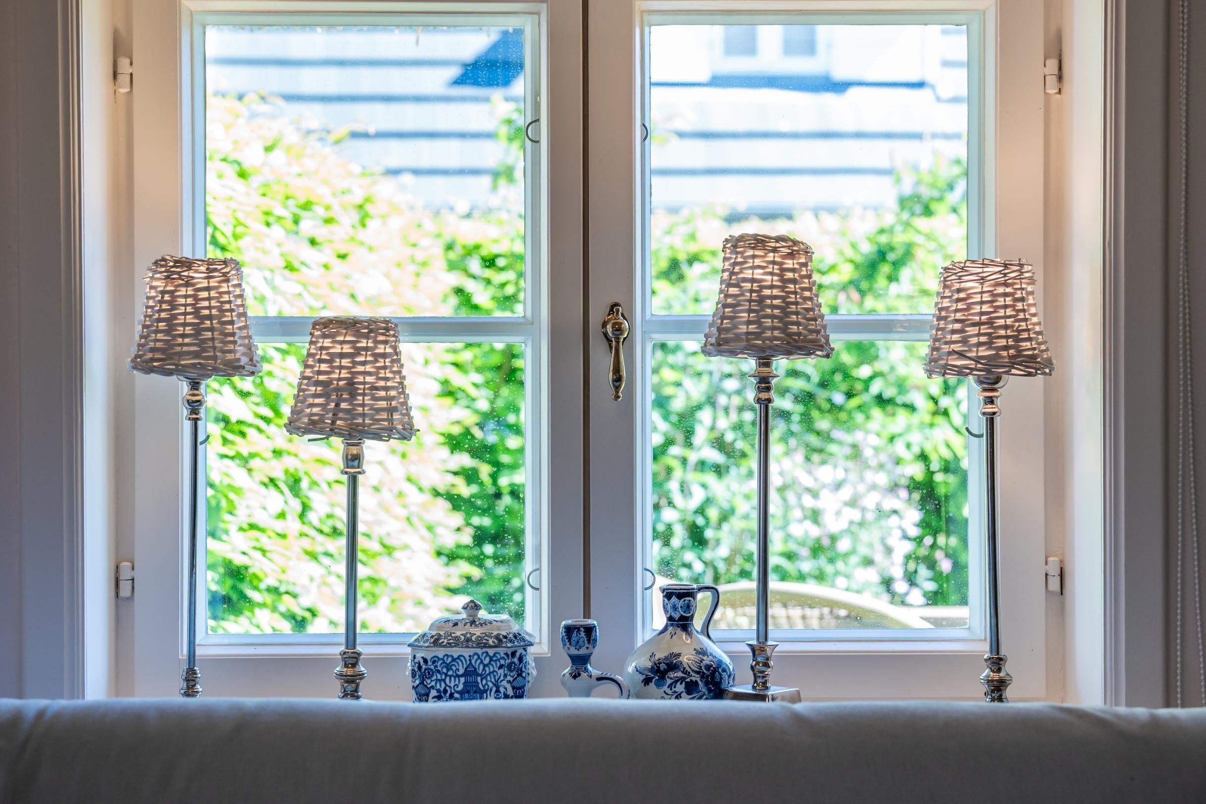 Une fenêtre, quatre lampes et un vase posés sur une table.