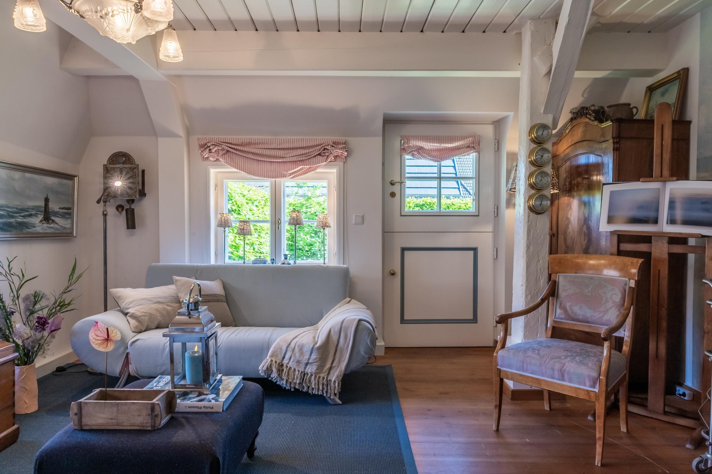 Un salon chaleureux avec un canapé, un fauteuil, une cheminée et une horloge au mur.