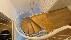 Eine Wendeltreppe mit Holzhandlauf und weißen Metallspindeln.