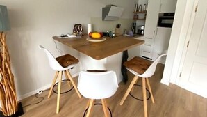 Eine moderne Küche mit einer Holztischinsel, weißen Stühlen und einer Pendelleuchte.