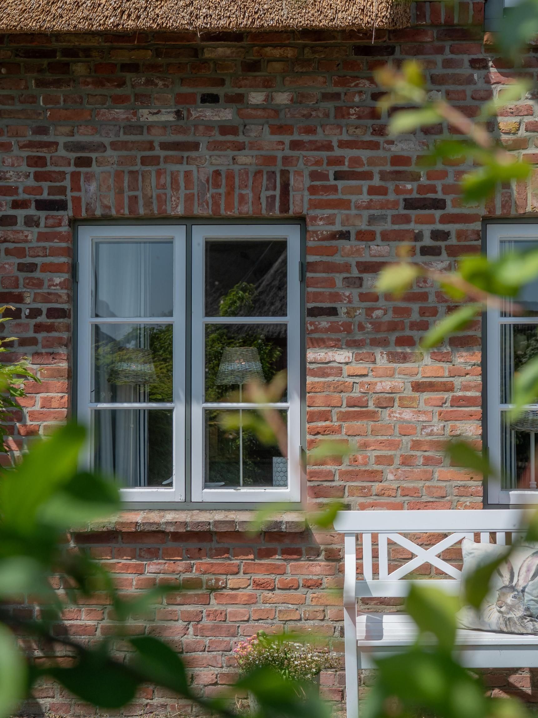 Et murstenshus med et hvidt vindue og en hvid veranda.