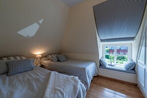 Ein Schlafzimmer mit zwei Betten, einer Sitzbank am Fenster mit Blick und einem Projektor an der Wand.