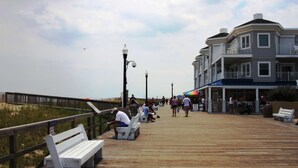 A wooden boardwalk with benches, a railing, and buildings with balconies. - First Floor Contemporary with Top Bay View, Pool, Tennis & Free Activities Including Golf and More. (Ocean View)