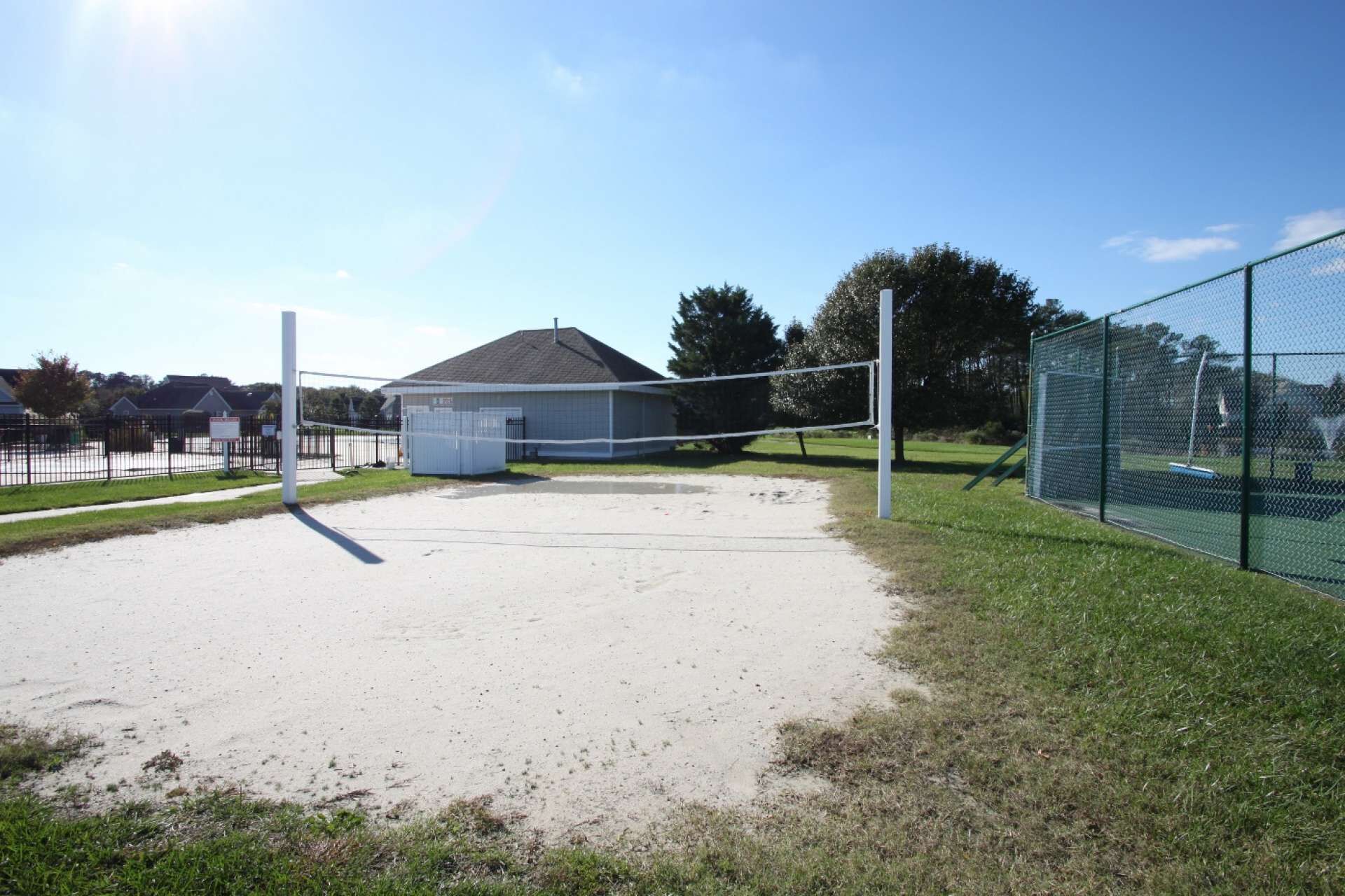A volleyball court with a net, a small shed, and a chain-link fence.