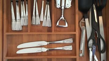 Un cajón con diversos utensilios de cocina, como cucharas, espátulas y un par de tijeras.