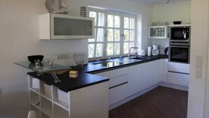 A modern kitchen with white cabinetry, a black countertop, and a window providing natural light.