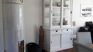 A living room with a white cabinet, a round white pillar, and a wicker chair.