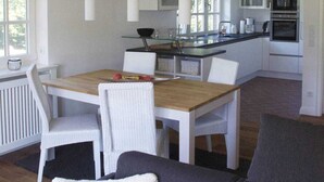 A modern kitchen with white cabinetry, a central island, and hanging pendant lights.