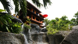 A waterfall cascading over rocks with a building in the background. - Sea Breeze Resort (Ko Pha-ngan)