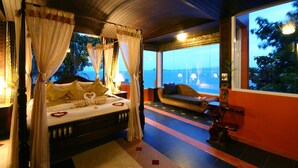 A four-poster bed with a canopy, a sofa, and a wooden bench in a room with a view of the ocean. - Sea Breeze Resort (Ko Pha-ngan)