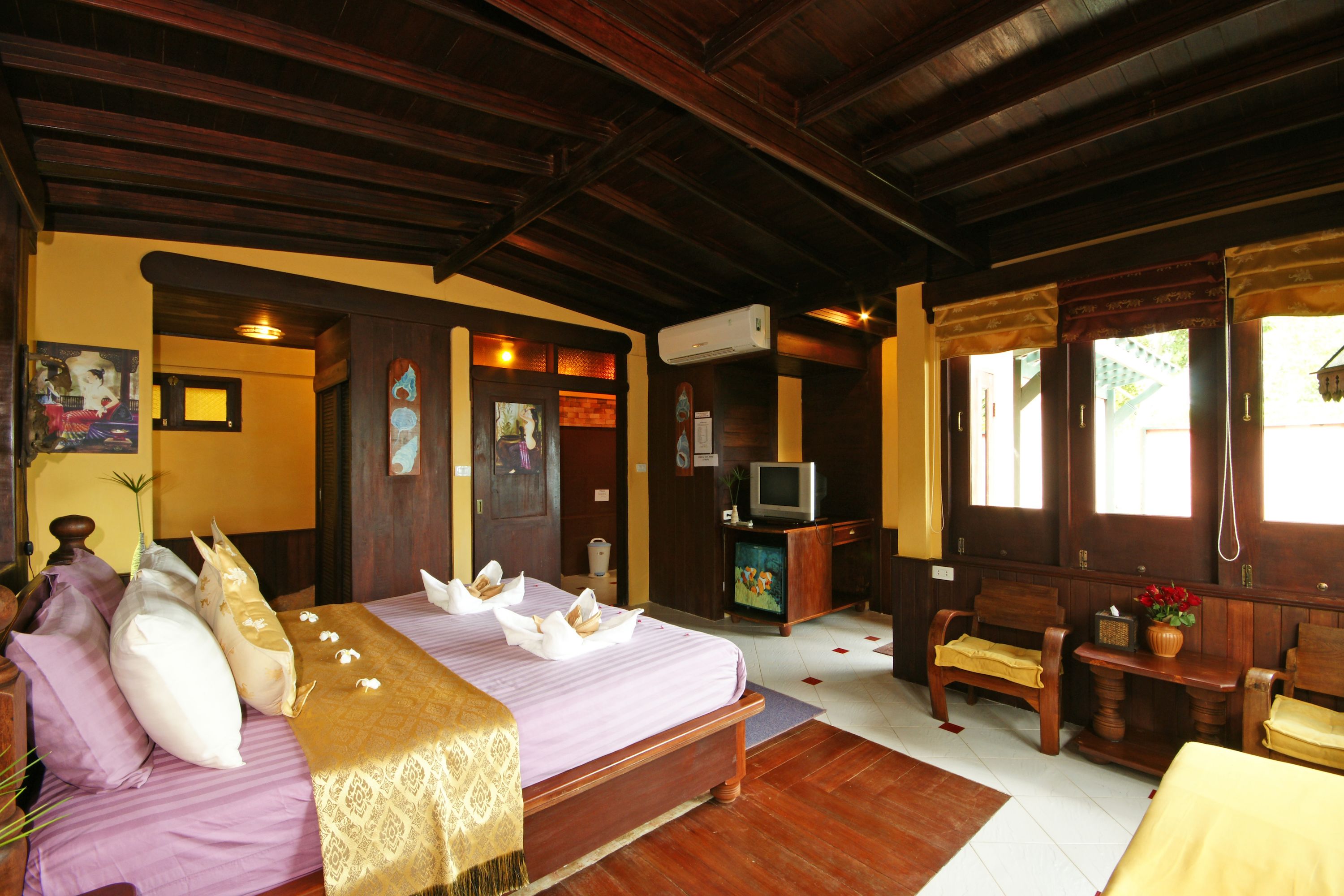 A room with a bed, wooden furniture, a television, and a window.