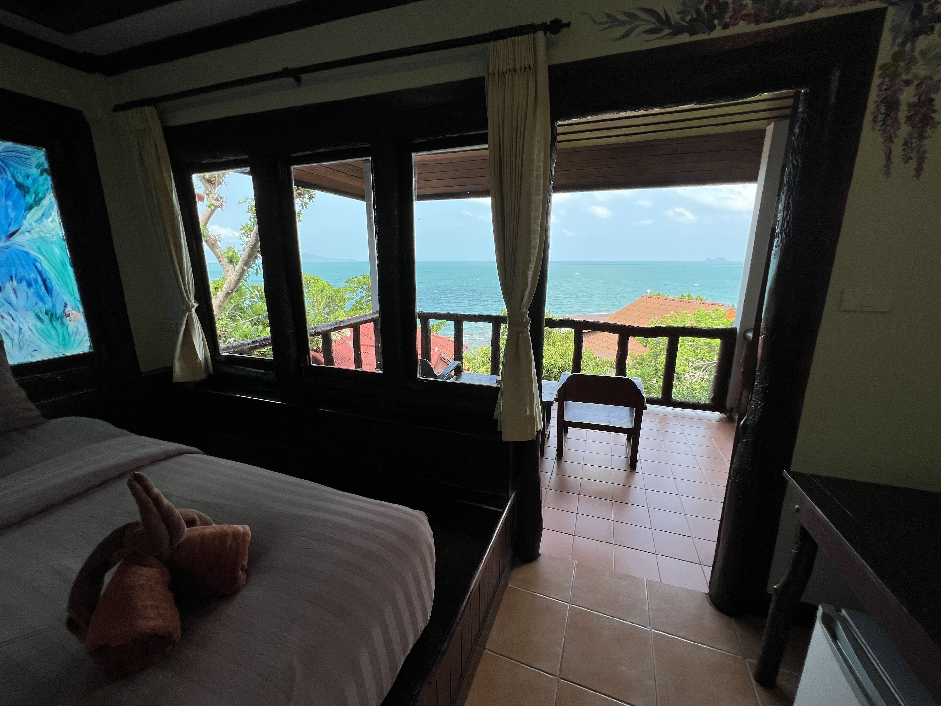 Un dormitorio con cama, una silla y vista al mar.