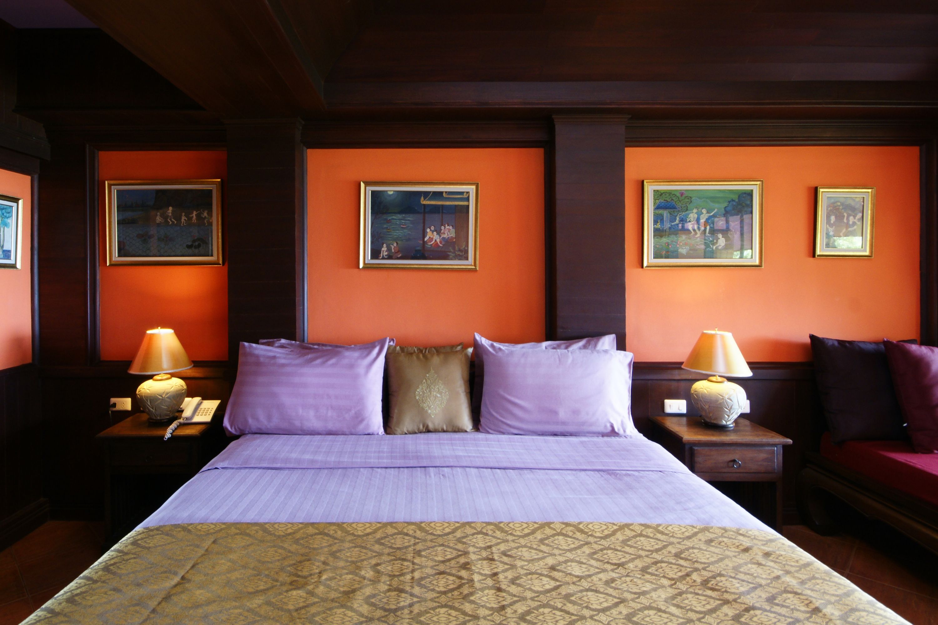 A hotel room with a large bed, two nightstands, two lamps, and three framed pictures on the wall.