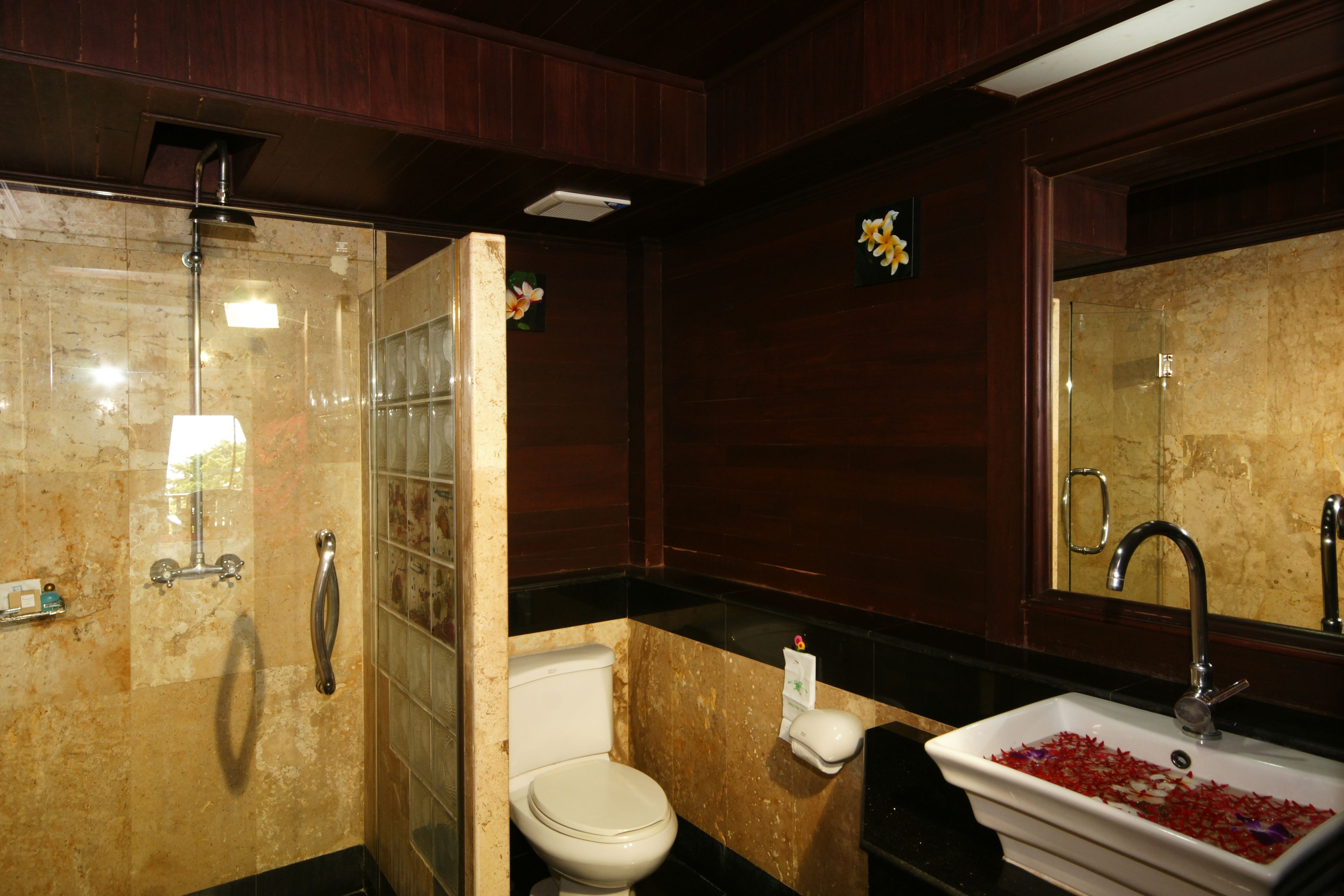 A bathroom with a glass-enclosed shower, a toilet, and a sink with a marble countertop.