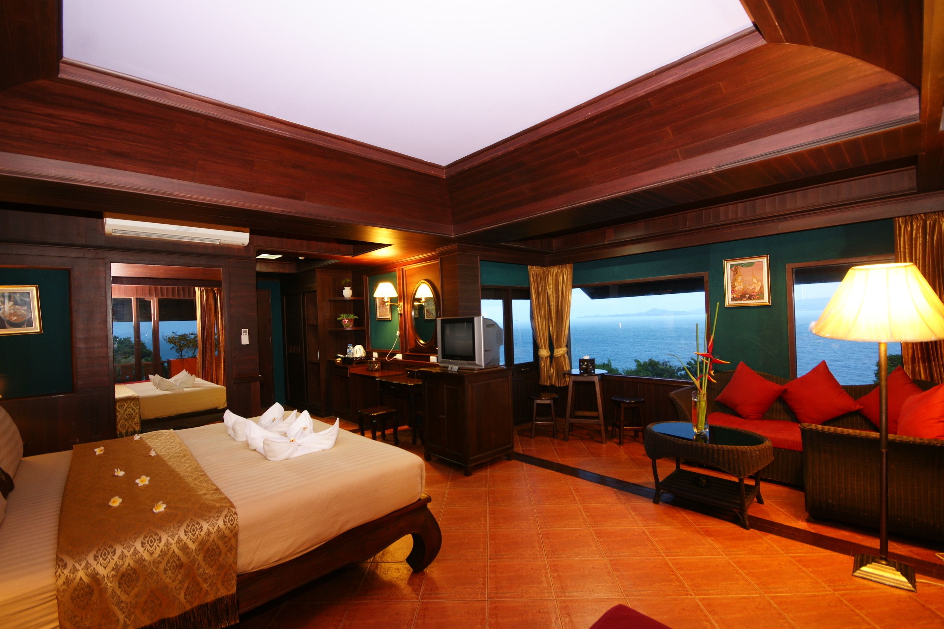 A hotel room with a large bed, a desk with a computer, a sofa, and a view of the ocean.