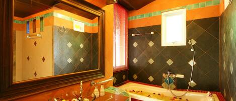 A bathroom with a glass bowl on the counter, a bathtub, and a mirror.