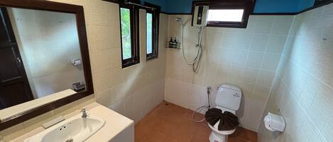 A bathroom with a sink, toilet, shower, and a window.