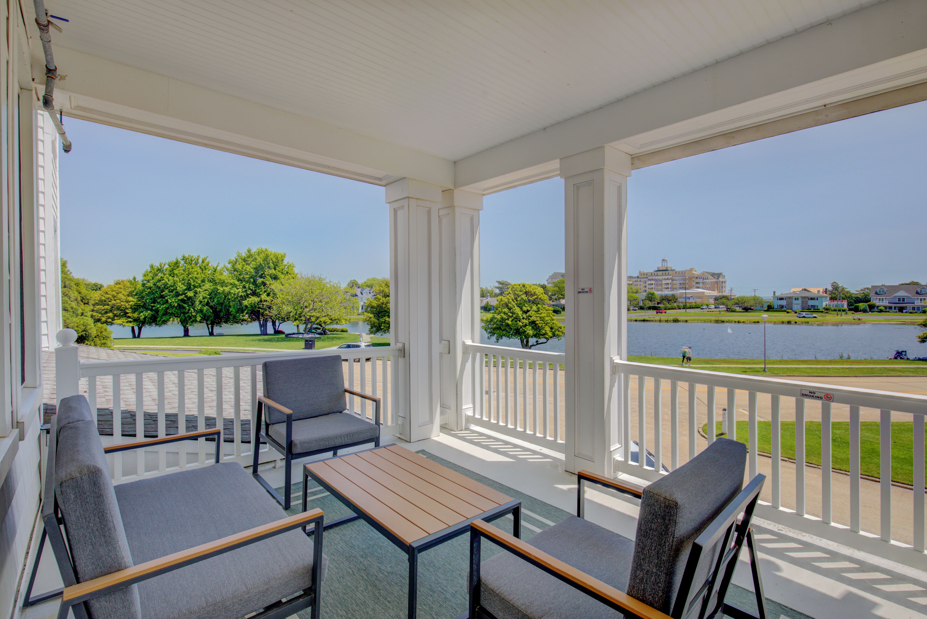 A covered outdoor seating area with a view of a lake and buildings in the distance.