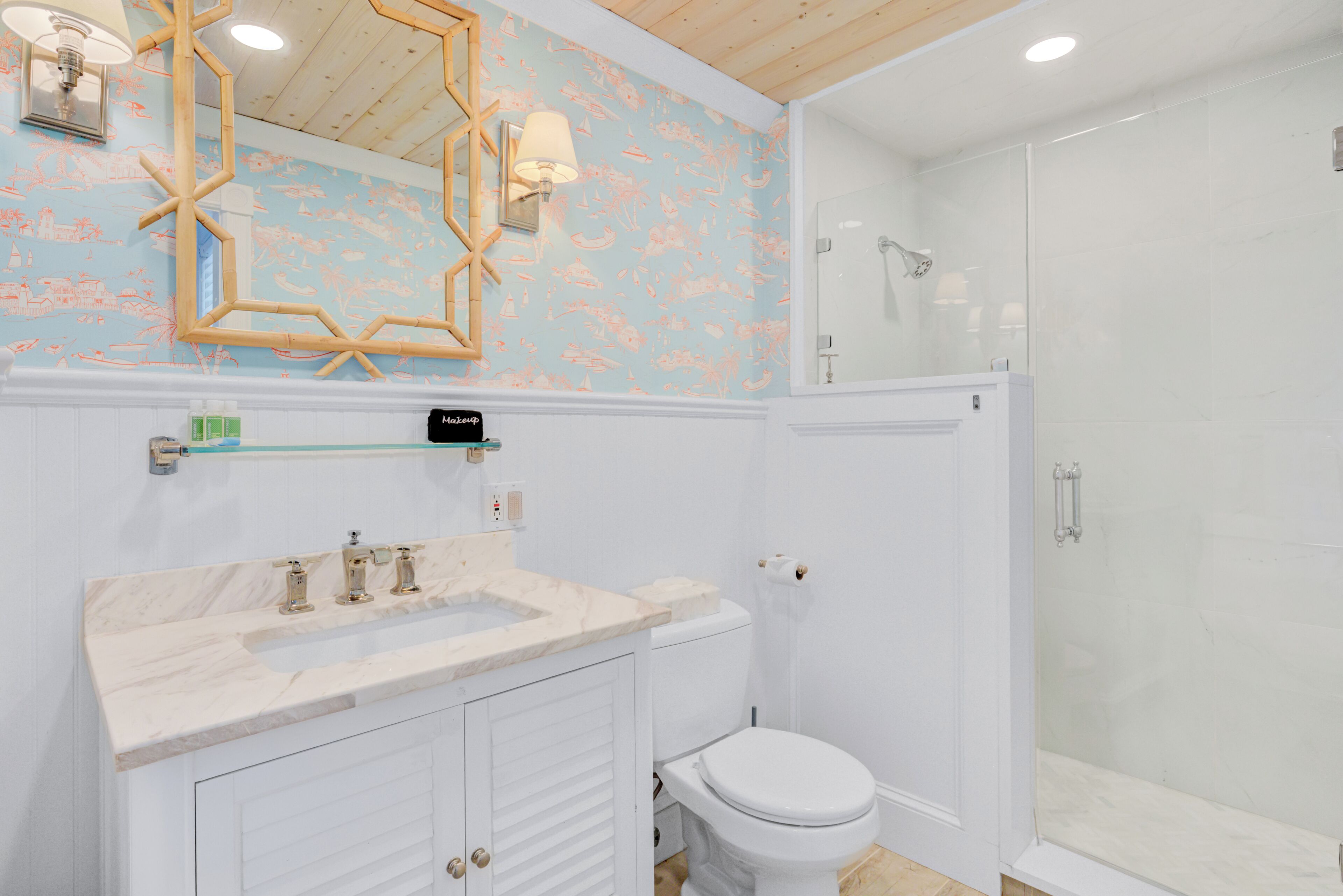 A bathroom with a white toilet, a sink with a marble countertop, and a shower area.