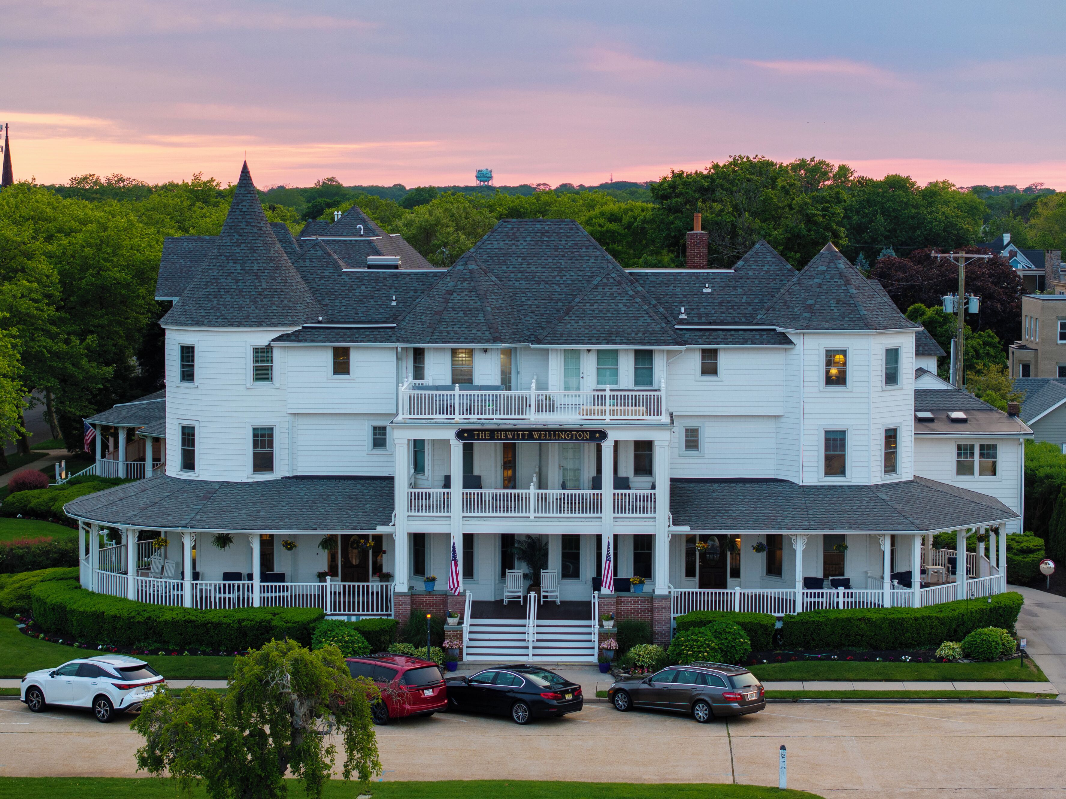 A large, white, multi-story building with a balcony and a sign reading "The Hewitt Wellington."