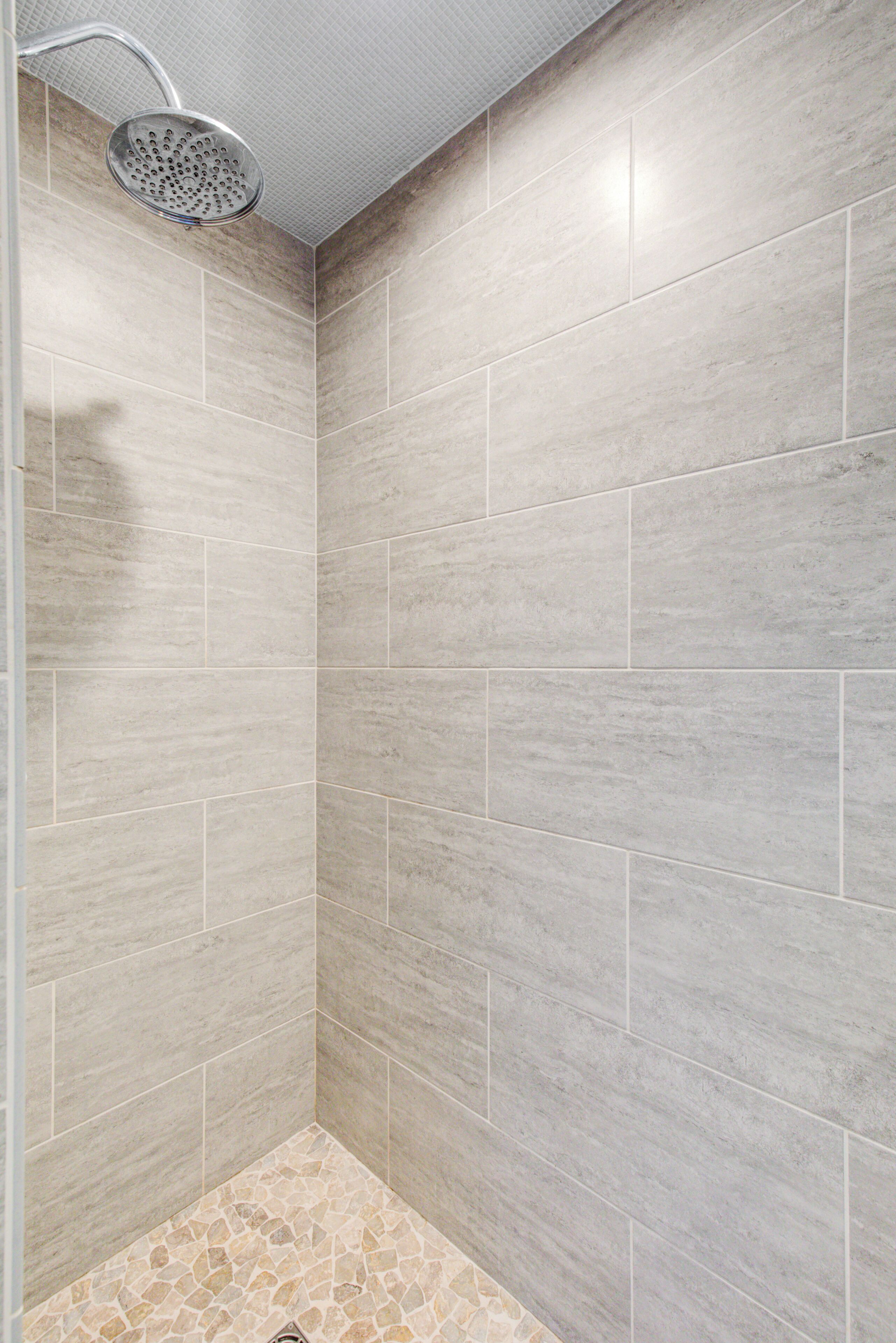 A shower area with a handheld showerhead and tiled walls.