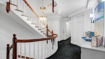 A staircase with white balusters and wooden handrails, a chandelier, and a black polka dot floor.