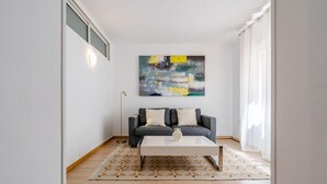 A modern living room with a grey sofa, white cushions, a white coffee table, and a large abstract painting on the wall. - Hotel Agur (Fuengirola)