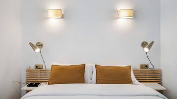 Un dormitori amb un llit, dues làmpades de nit, una taula de nit i una làmpada penjada a la paret.