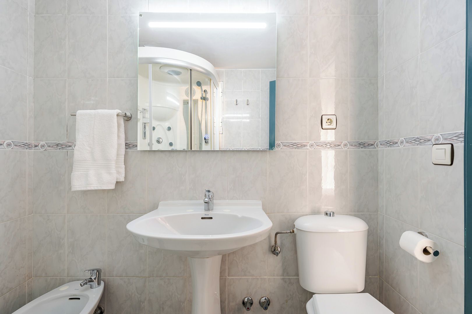 Un baño con lavamanos, inodoro y zona de ducha.