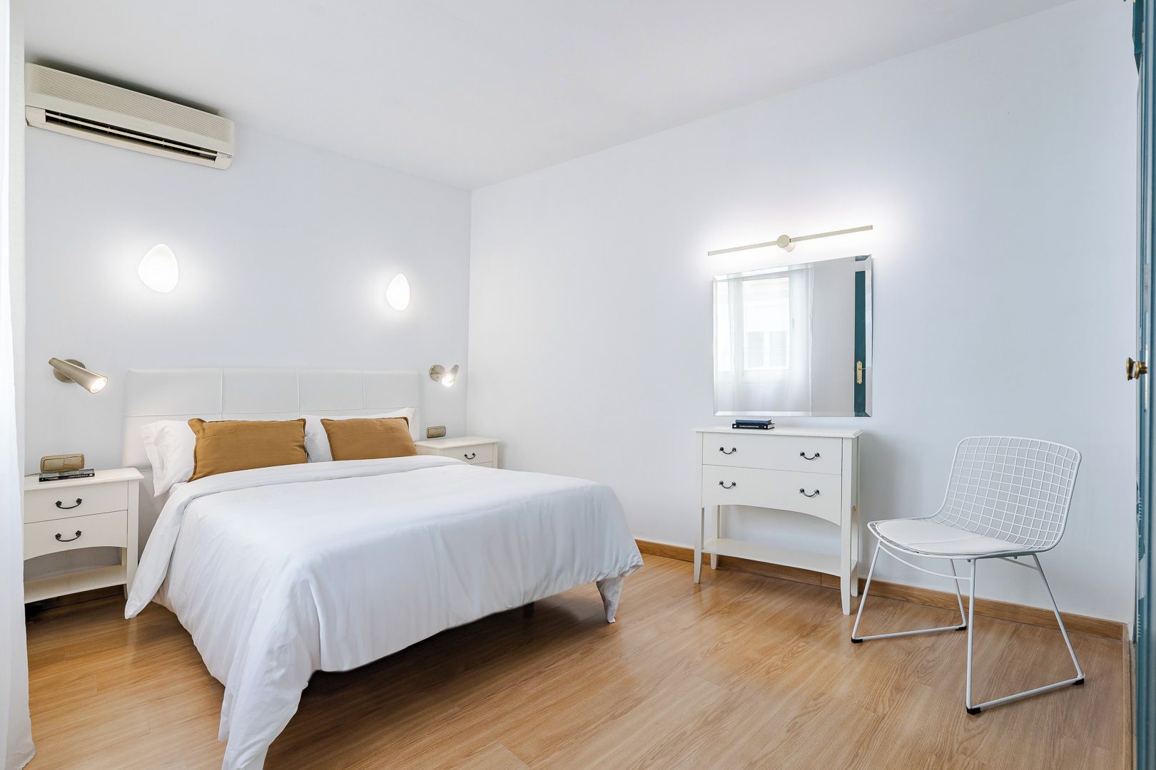 Une chambre à coucher comprenant un lit, des tables de chevet, une commode, une chaise et un miroir.