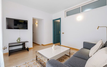 A modern living room with a flat-screen TV, a coffee table, a sofa, and a lamp.