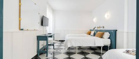 Ein Hotelzimmer mit Schachbrettmuster-Boden, einem Schreibtisch mit Stuhl, zwei Betten mit Kopfteilen, einem Fernseher und Wandleuchten.