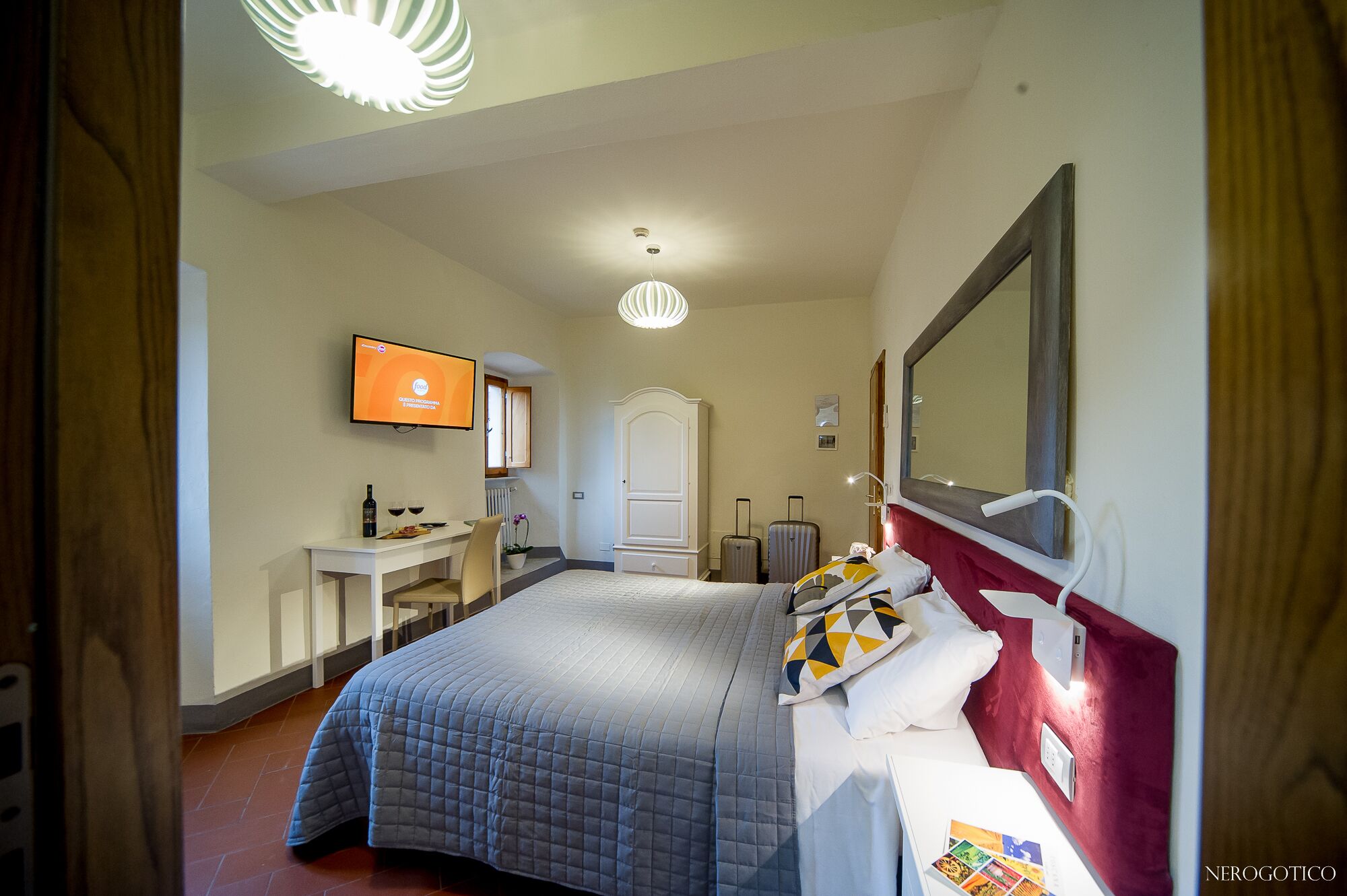 Ein Hotelzimmer mit Bett, Schreibtisch, Stuhl, Fernseher und Kleiderschrank.