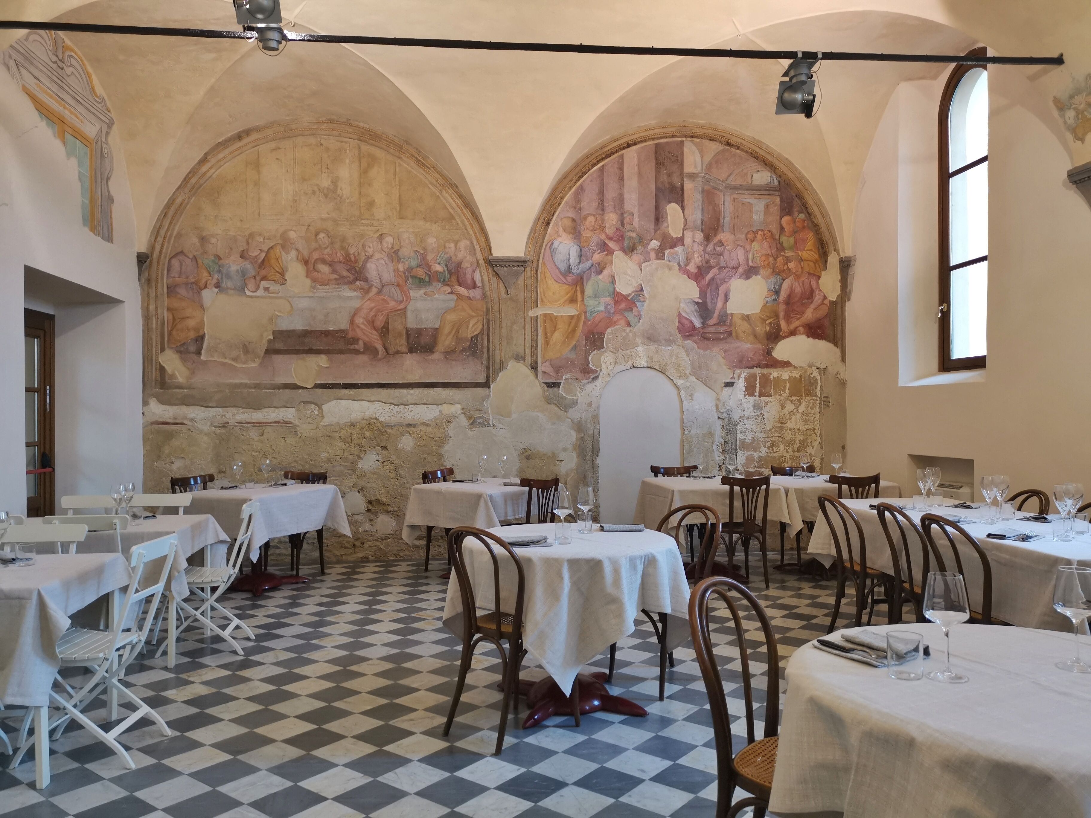 Un comedor con mesas, sillas y piso a cuadros.